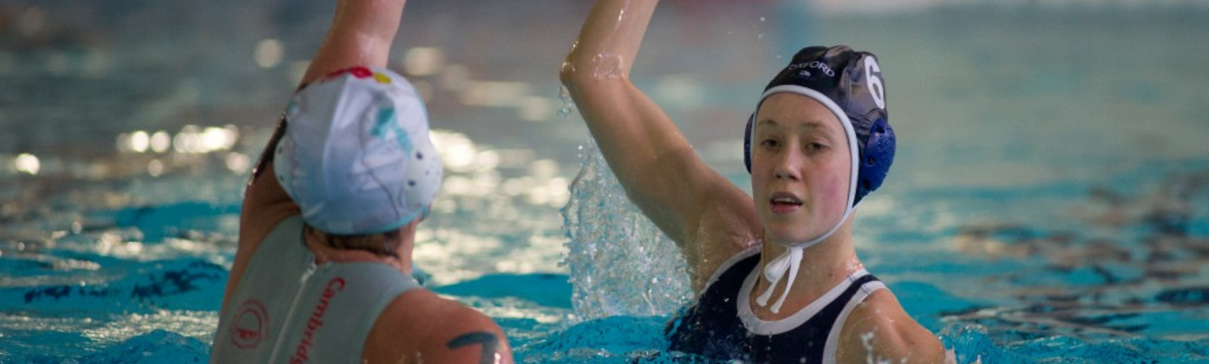 Two women playing water polo in the Oxford vs Cambridge Varsity match